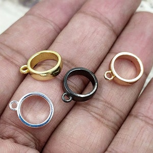 May include: Four metal rings with a loop on the top. The rings are gold, silver, black, and gold. The rings are all the same size and shape.