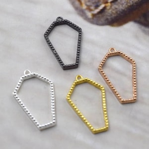 Puede incluir: Cuatro colgantes de metal en forma de ataúd en diferentes colores: negro, plateado, dorado y dorado rosa. Cada colgante tiene un borde de cuentas.