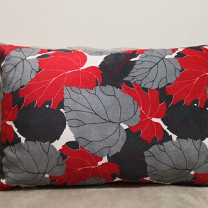 May include: Red and gray leaf patterned throw pillow. The pillow is rectangular and has a white background.