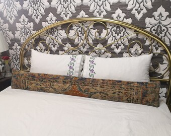 May include: A gold metal headboard with a decorative scroll design. The headboard is on a bed with white bedding and a patterned bolster pillow.