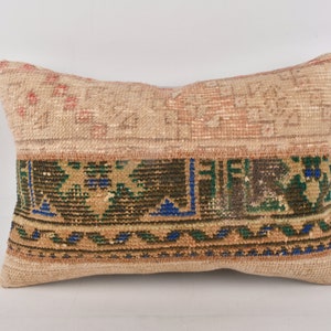 Peut inclure: Un coussin rectangulaire avec un fond beige et un motif géométrique coloré. Le motif présente des couleurs vertes, bleues et brunes.