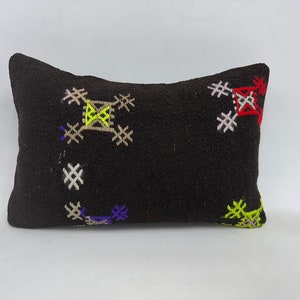 May include: A black pillow with colorful embroidered geometric patterns. The pillow is made of a soft, textured fabric and has a rectangular shape.