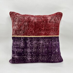 May include: A square decorative pillow with a two-tone design. The top half is a deep red, and the bottom half is a rich purple. A thin gold-colored line separates the two colors. The pillow has a textured, vintage appearance.