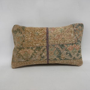May include: A rectangular pillow with a brown, green, and beige patterned fabric. The pillow has a subtle purple seam down the center.