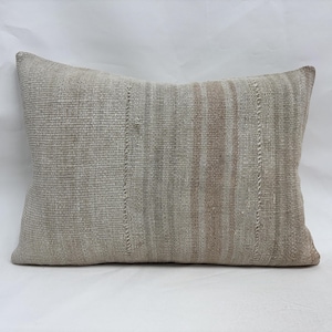 May include: Rectangular beige pillow with vertical stripes in shades of beige and brown. The pillow has a textured appearance and is likely made of woven fabric. The pillow is a decorative item for a bed or sofa.