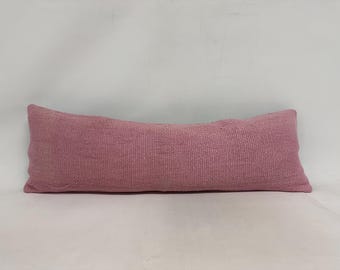 May include: A long, rectangular pink pillow with a textured fabric.