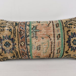 May include: A rectangular pillow with a beige background and a colorful geometric pattern. The pattern features shades of blue, green, and brown.