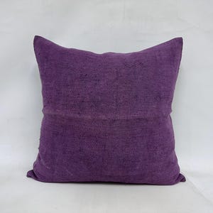 May include: A purple throw pillow with a soft, textured fabric. The pillow is square and has a simple design.