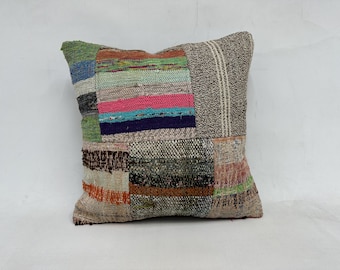 May include: A patchwork pillow with a variety of colors and textures, including brown, green, blue, pink, and white.