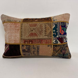 May include: A rectangular pillow with a patchwork design. The pillow is made of different colored fabrics with geometric patterns. The pillow is beige, brown, red, blue, and green.