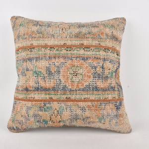 May include: A square throw pillow with a woven fabric cover. The pillow has a blue, green, and orange geometric pattern.