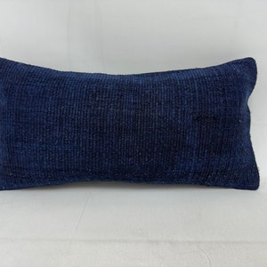 May include: A dark blue rectangular pillow with a textured woven fabric. The pillow is lying flat on a white surface.
