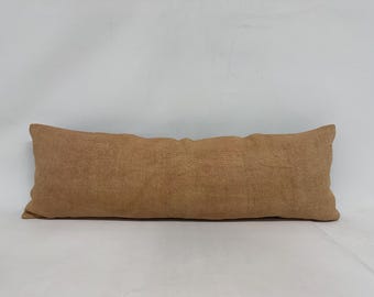 May include: A long, rectangular brown pillow with a textured fabric.