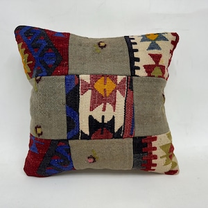 May include: A patchwork pillow with a geometric design in shades of red, blue, green, and yellow. The pillow is made of a soft, woven fabric and has a square shape.