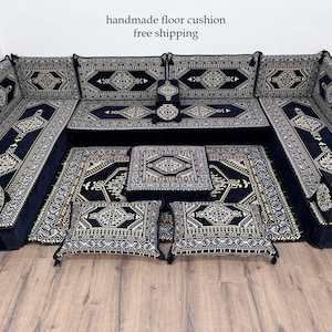 Peut inclure: Ensemble de coussins de sol modulaires bleu marine avec des motifs géométriques complexes blancs et beiges. L'ensemble comprend de grands coussins rectangulaires, des coussins carrés plus petits et un coussin central carré.