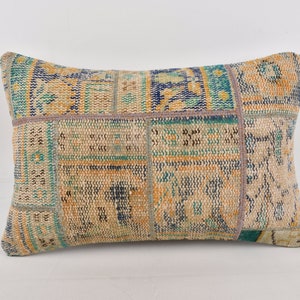 May include: A rectangular throw pillow with a patchwork design featuring a variety of colors, including beige, blue, and green. The pillow is made from a woven fabric with a textured surface.