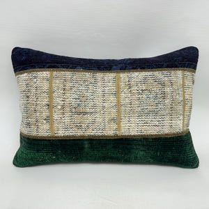 May include: Rectangular decorative pillow with a navy blue top, a beige and patterned center, and a dark green bottom. The pillow has a textured appearance, with visible stitching and a soft, plush feel. The pillow is designed for home decor.