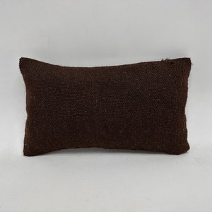 May include: A brown rectangular pillow with a textured woven fabric surface.