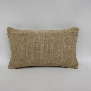 May include: A beige rectangular pillow with a woven texture. The pillow is made of a natural fabric and has a simple design.