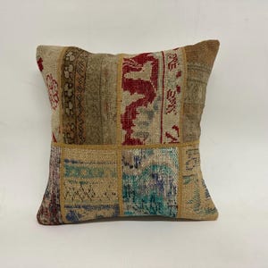 Pode incluir: Uma almofada quadrada de patchwork com uma variedade de cores e padrões, incluindo vermelho, azul e bege. A almofada é feita de um tecido macio e tecido e tem um visual vintage único.