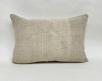 May include: A rectangular beige pillow with a textured surface. The pillow has a seam running down the center and is made of a woven fabric. The pillow is a neutral color and would complement various decor styles.