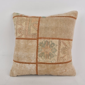 May include: A beige and brown patterned throw pillow with a square design. The pillow is made of a soft, woven fabric.