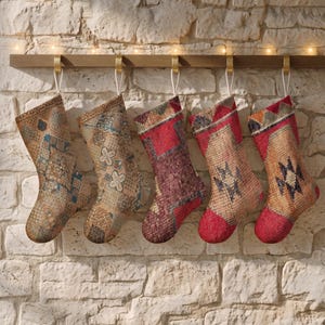 May include: Five Christmas stockings hanging from a wooden rail, each featuring a unique woven pattern. The stockings display various color palettes including shades of tan, blue, deep red, and orange, with intricate geometric and floral motifs.