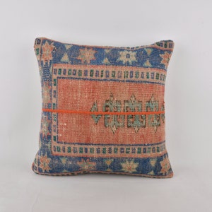 May include: A square pillow with a blue, green, and orange patterned fabric. The pillow has a red and orange border.