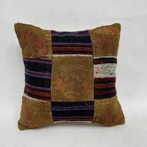 May include: A brown and black patterned throw pillow with a geometric design. The pillow is made of woven fabric and has a square shape.