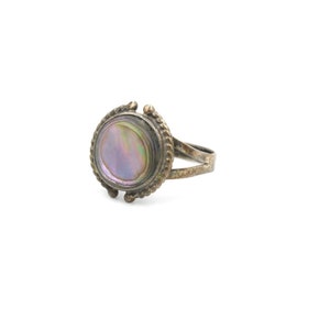 May include: A silver ring with a round iridescent abalone shell set in a decorative bezel.