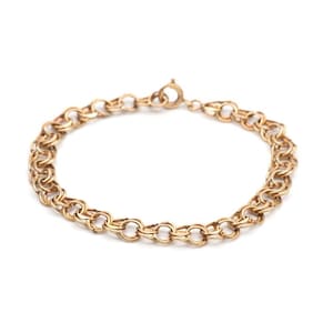 May include: A gold-toned metal chain bracelet featuring a series of interlocking circular links. The bracelet is arranged in a circular shape and includes a small, circular spring-ring clasp mechanism at the top for securing the piece together.