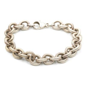 May include: A silver chain bracelet with a springy, coiled link design.