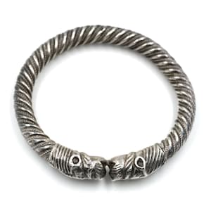 Könnte beinhalten: Ein silbernes Armreif-Armband mit einem gedrehten Seil-Design und zwei stilisierten Tierkopfenden.