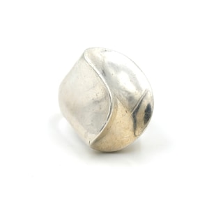 May include: A silver ring with a unique, abstract design. The ring is made of a smooth, polished metal and has a rounded, organic shape.