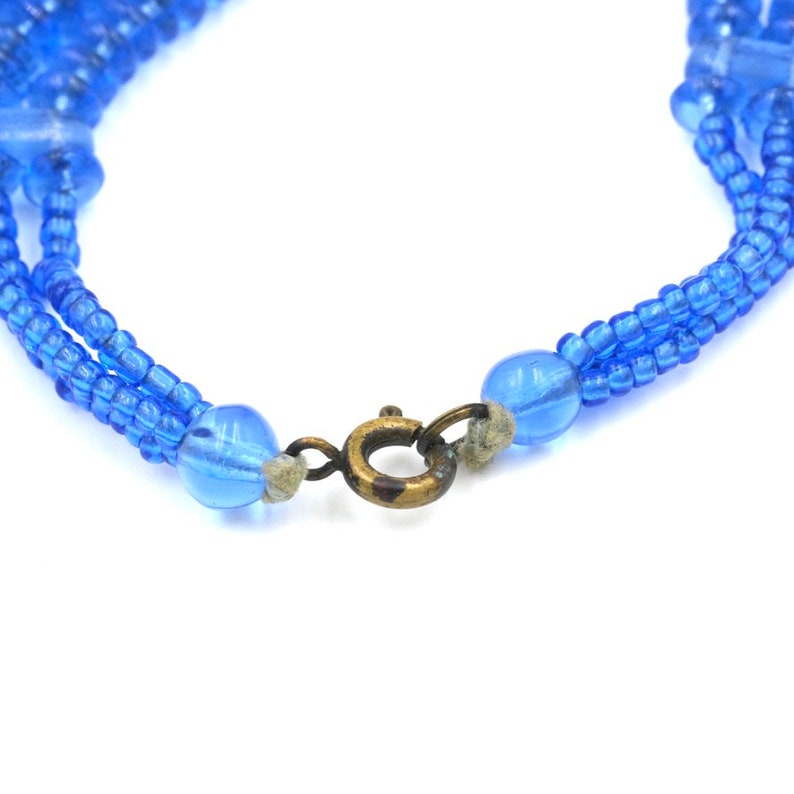 Op de afbeelding: Een meerstrengige ketting gemaakt van blauwe glazen kralen met een messing sluiting.