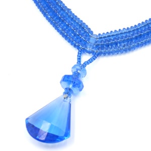Op de afbeelding: Een blauwe kristallen ketting met een traanvormige hanger. De ketting is gemaakt van meerdere strengen kleine blauwe kralen.