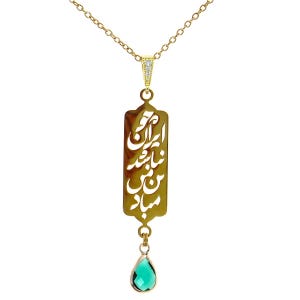 May include: A gold-colored necklace with a rectangular pendant featuring ornate cut-out calligraphy. The pendant is suspended from a delicate chain and has a teardrop-shaped, emerald-green gemstone at the bottom.