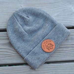 May include: Gray beanie with a brown leather patch that says "Fear the Beard" with a bearded face inside the circle.