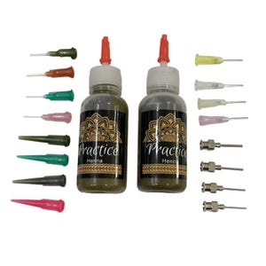 May include: Two bottles of green henna practice paint with red caps and the words "Practice Henna" on the labels. The bottles are surrounded by a variety of small, clear, plastic tubes with needles attached.