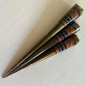 May include: Three brown henna cones with gold and orange labels that say "Jagua Henna".
