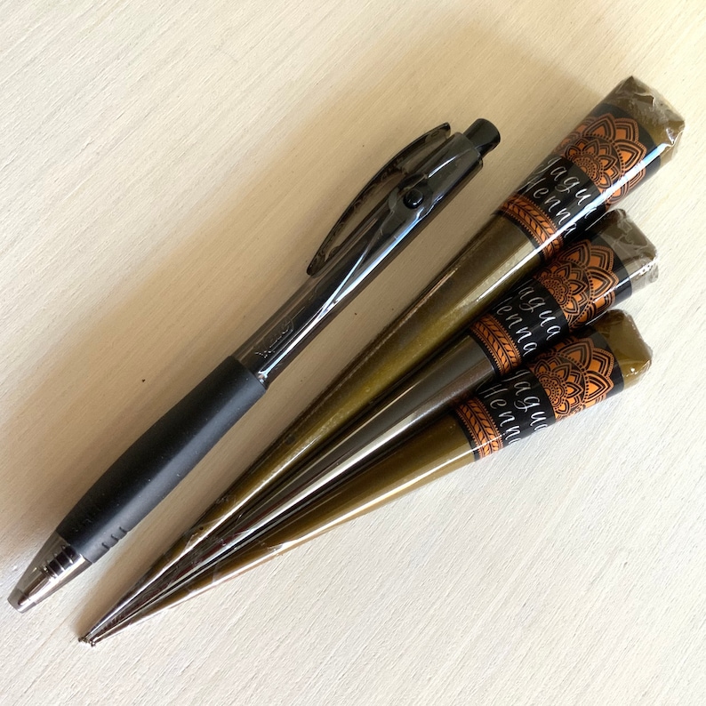 May include: Four brown henna cones with black and gold labels that say "Jagua Henna" and a black pen.