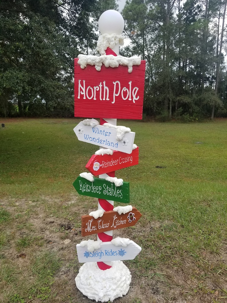 Picture shows 6 foot tall Christmas signpost assembled outdoors covered in snow.