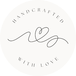 May include: A white circle with the text "HAND CRAFTED WITH LOVE" around the edge. A stylized heart with a swirl is in the centre.