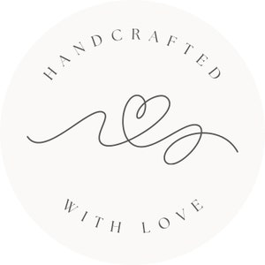 May include: A circular logo with the words "HANDCRAFTED" arched at the top and "WITH LOVE" at the bottom. A continuous line drawing of a heart and flowing lines is in the center, all in a dark gray color against a cream background.