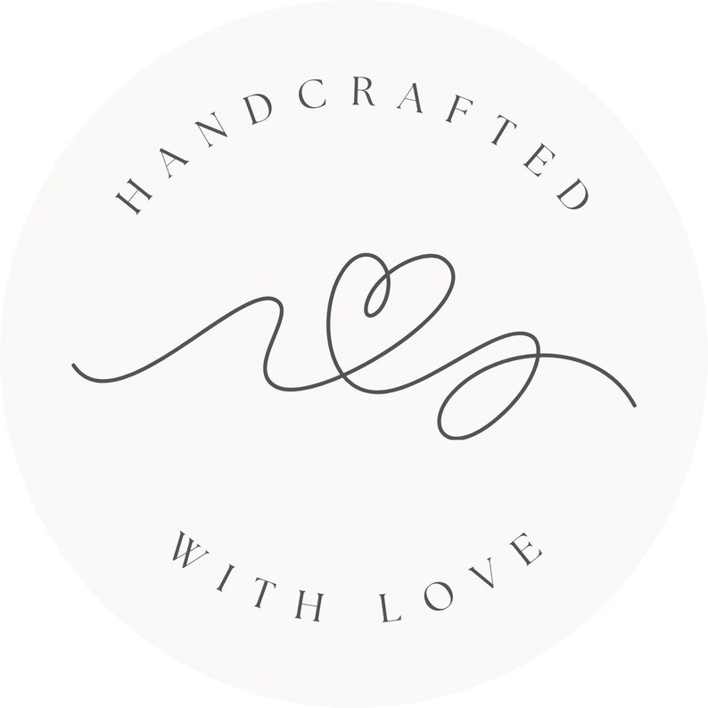 May include: A circular logo with the words "HANDCRAFTED" arched at the top and "WITH LOVE" at the bottom. A continuous line drawing of a heart and flowing lines is in the center, all in a dark gray color against a cream background.