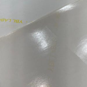 Pode incluir: Um close-up de uma superf&iacute;cie branca texturizada com as palavras "YBL LAB" impressas em amarelo.