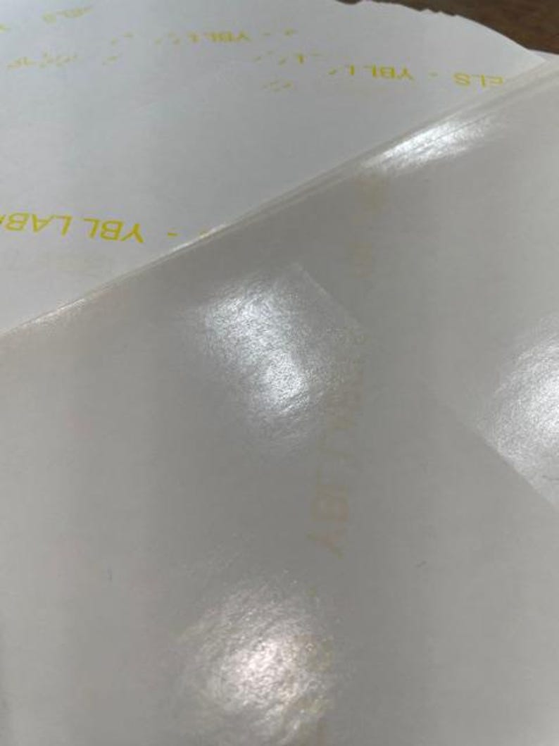 Pode incluir: Um close-up de uma superf&iacute;cie branca texturizada com as palavras "YBL LAB" impressas em amarelo.