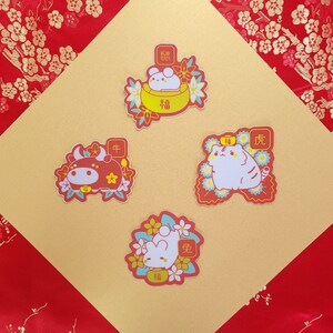 May include: Four colorful stickers featuring Chinese New Year animal illustrations. The stickers feature a red ox, a white cat, a white rabbit in a bowl, and a white rabbit holding a peach. Each sticker has a red background with gold accents and Chinese characters.