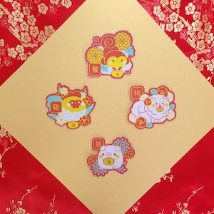 May include: Four colorful stickers featuring Chinese zodiac animals. Each sticker has a red background with gold accents and features a cartoon animal with a Chinese character for the animal's name. The animals are a monkey, a rooster, a dog, and a pig.