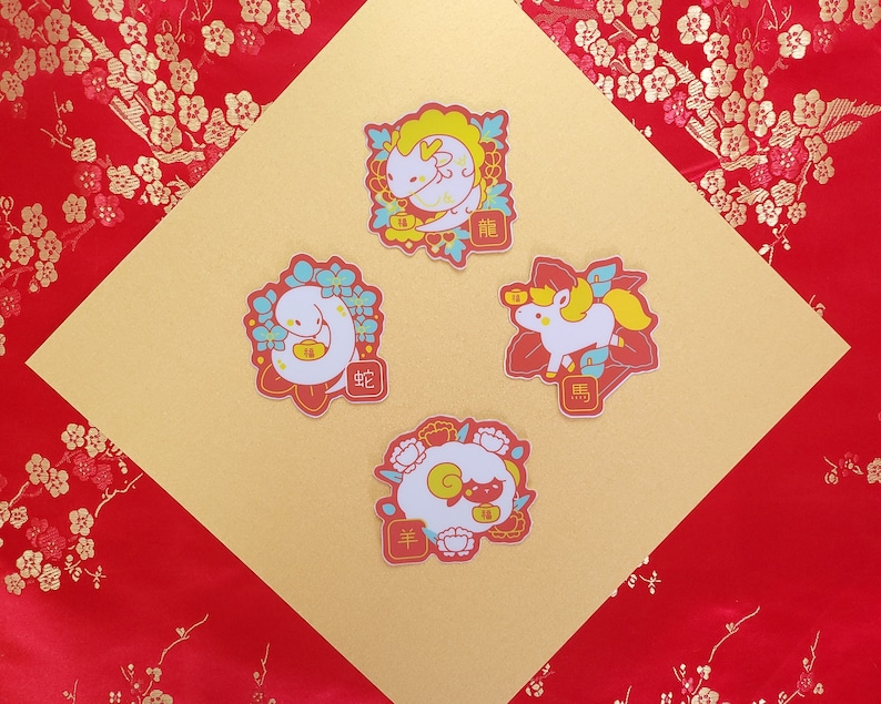 May include: Four colorful stickers featuring Chinese zodiac animals. The stickers are on a gold background with red floral patterns. The animals are a dragon, a snake, a horse, and a sheep. The stickers have Chinese characters on them.